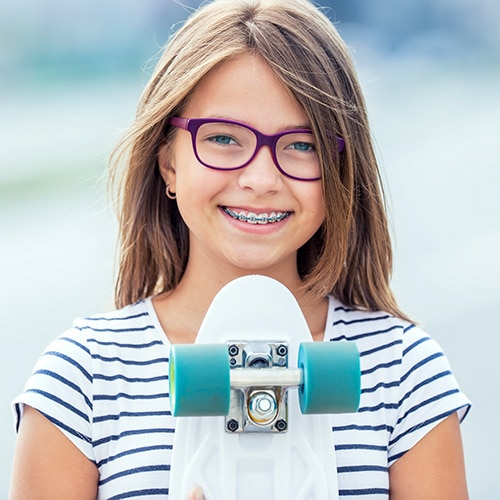 Teen smilng with braces while doing a skateboard