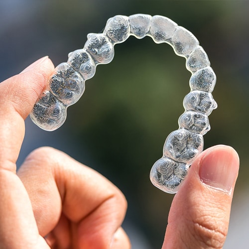 A person holding clear aligners close up