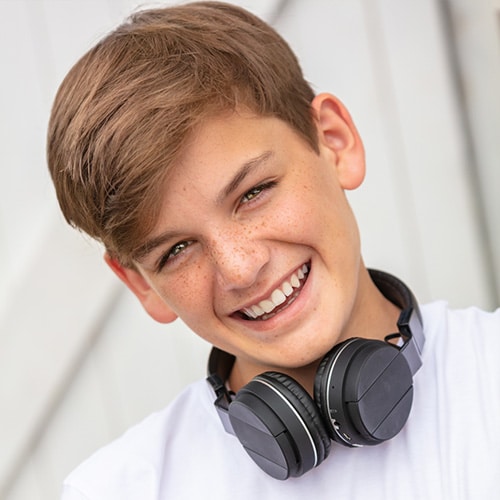 Teen smiling with headphones around his neck